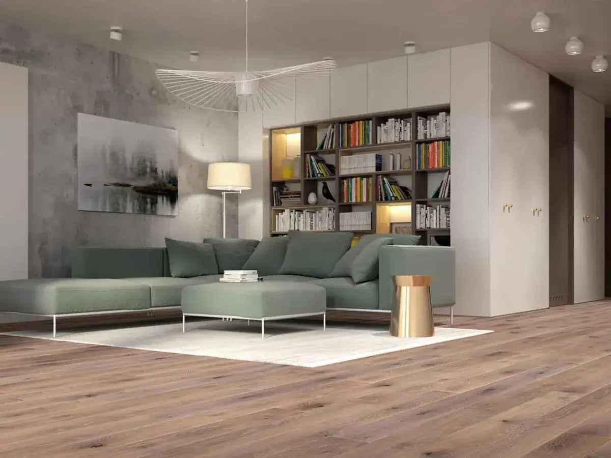 Nowoczesny salon w stylu naturalnym z zieloną kanapą, betonową ścianą i regałem pełnym książek.