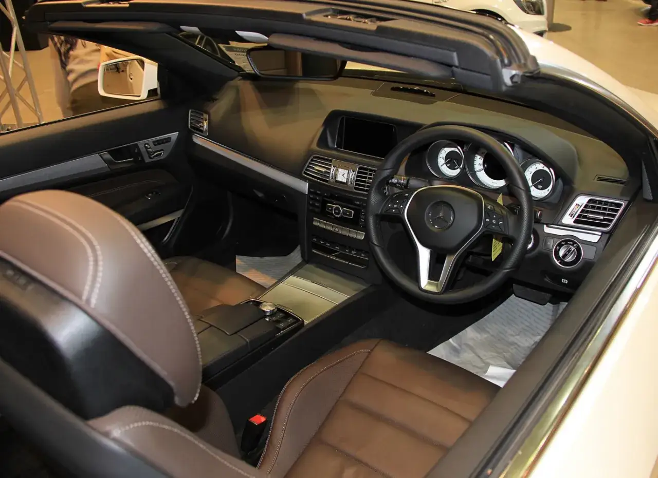 Wnętrze kabrioletu Mercedes W207 z brązową skórzaną tapicerką, czarną deską rozdzielczą i kierownicą.