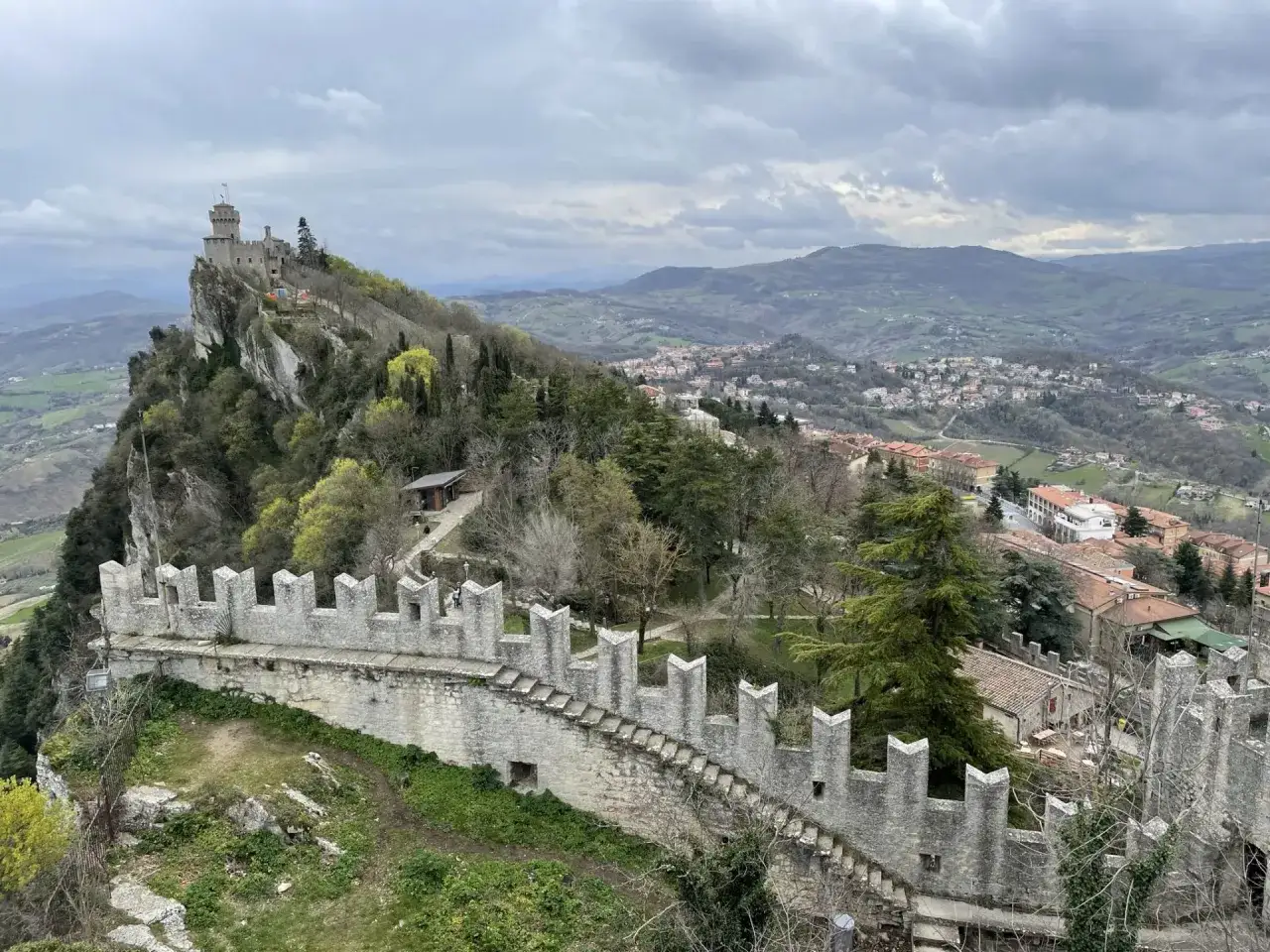 Widok na zamek Guaita i miasto San Marino, z kamiennym murem obronnym na pierwszym planie.