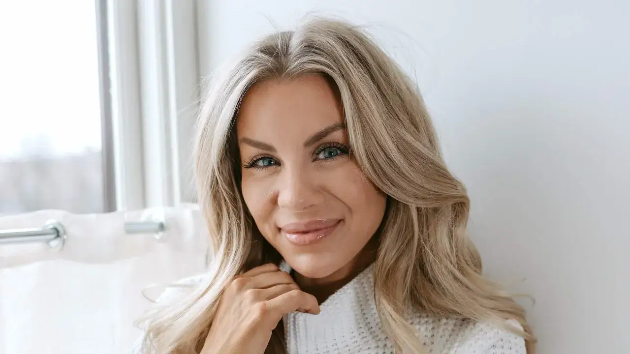 Fina Josefin ler mot kameran med sina blå ögon och blonda hår. Hon bär en vit stickad tröja.