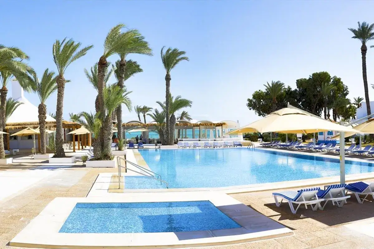 Słoneczny dzień w Djerba Resort (dawniej Vincci). Błękitny basen, palmy i leżaki zapraszają do relaksu.