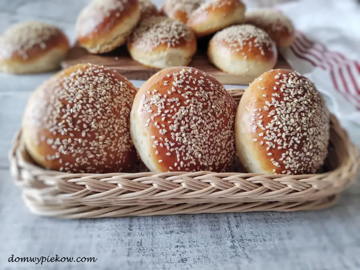 Świeżo upieczone bułki do burger&oacute;w, posypane sezamem, czekają w wiklinowym koszyku na pyszne nadzienie.