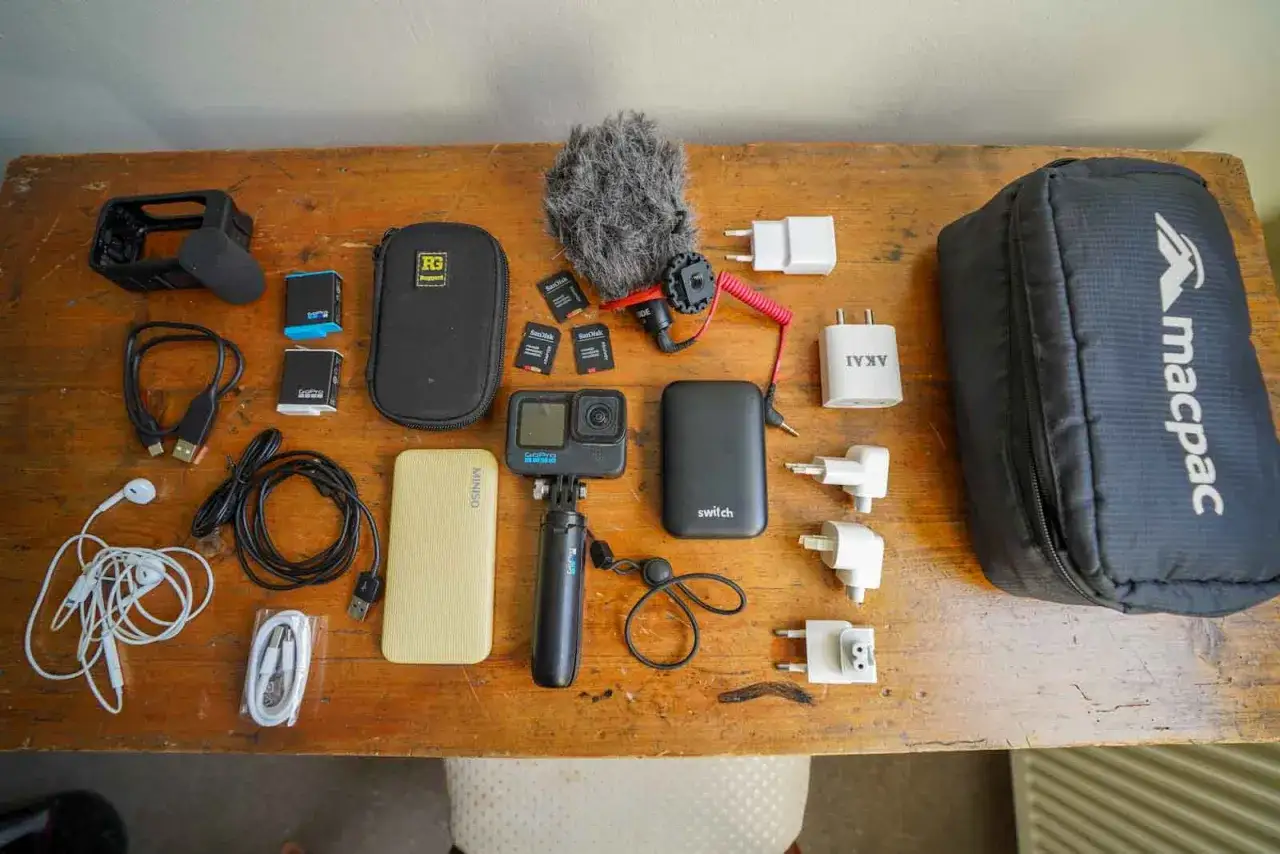 Zestaw elektroniki do samolotu: kamera GoPro, powerbank, mikrofon, karty pamięci, ładowarki i kable.