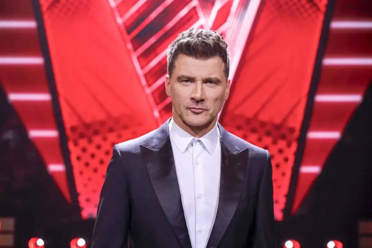Mężczyzna w garniturze na tle czerwonej sceny. Czy wiesz, ile ma lat Kammel?