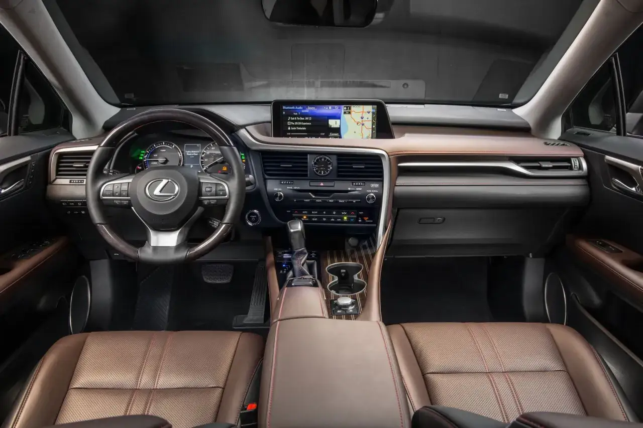 Wnętrze Lexus RX 450h z brązową skórzaną tapicerką, ekranem multimedialnym i kierownicą.