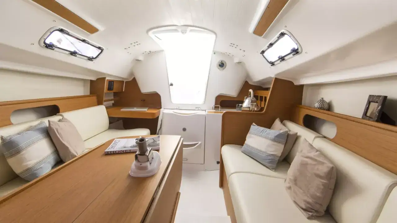 L'intérieur du voilier, premier 25, offre un espace lumineux avec des banquettes confortables, une table en bois et des hublots.