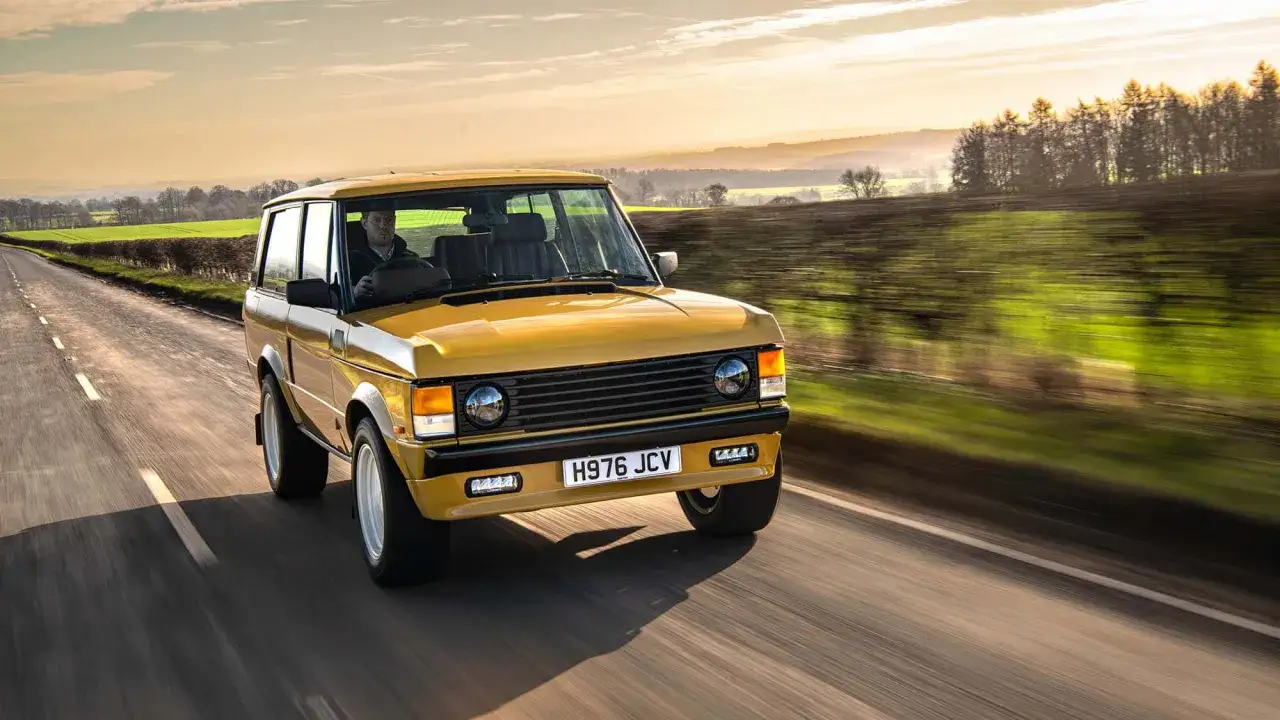 Gelber Range Rover 3-T&uuml;rer f&auml;hrt auf einer Landstra&szlig;e bei Sonnenuntergang.