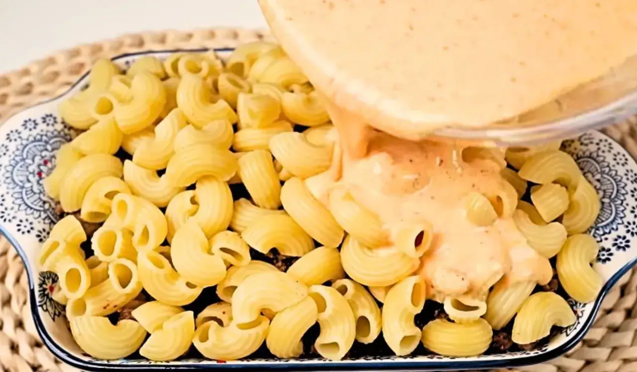 Sos serowy wylewany na makaron w naczyniu. Idealny sposób, jak podgrzać zapiekankę makaronową.