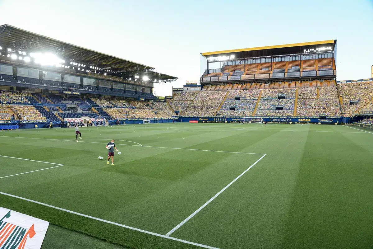 Piłkarze rozgrzewają się na murawie stadionu przed meczem La Liga. Trybuny wypełnione są kartonowymi podobiznami kibiców.