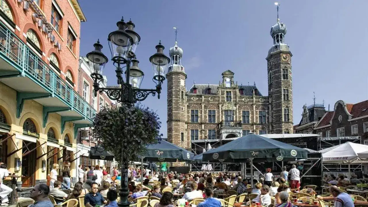 Lebhafter venlo markt mit vielen Menschen, die draußen sitzen. Im Hintergrund das historische Rathaus.