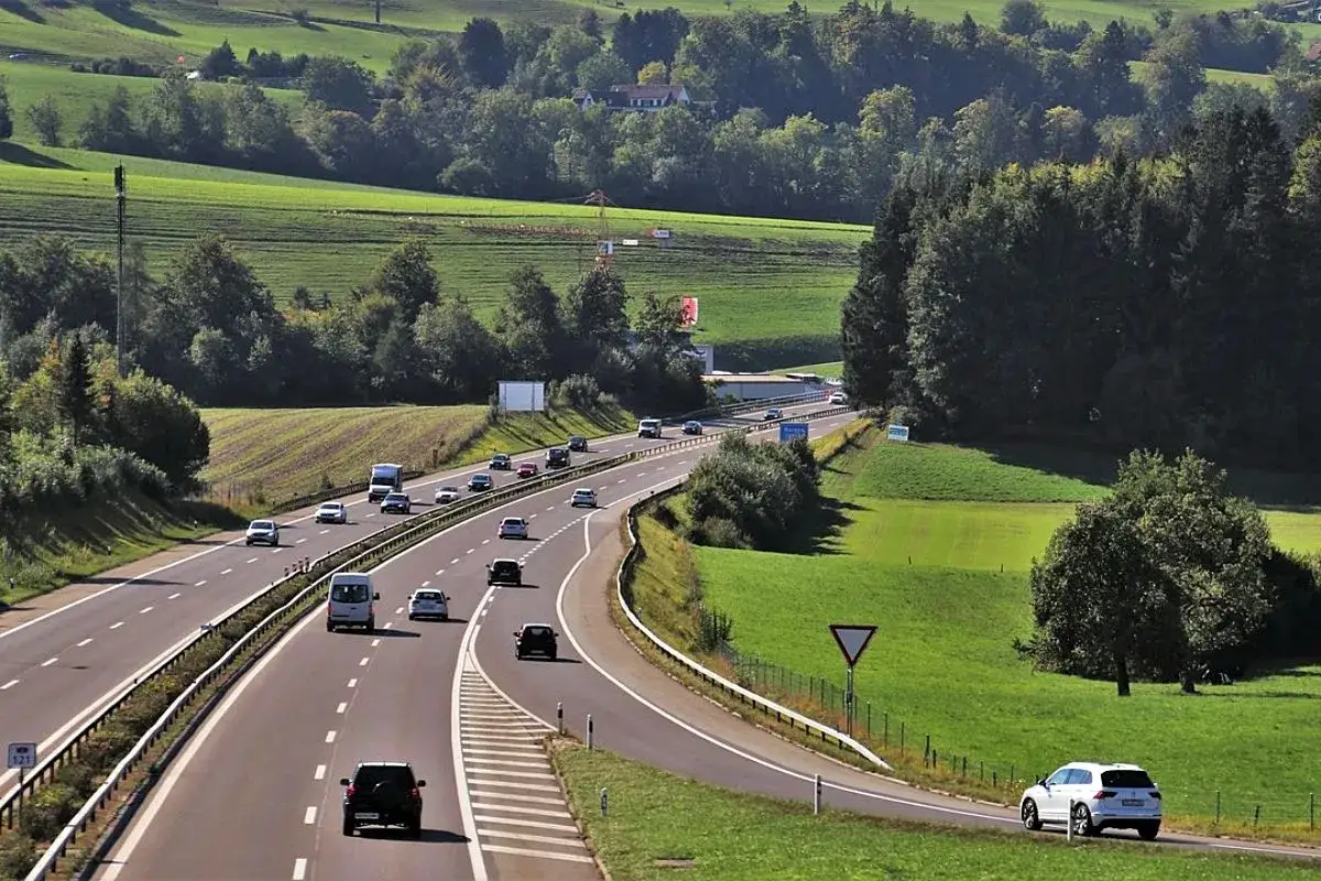 Coches circulan por una autopista en un paisaje verde. Para entrar en una autopista a qu&eacute; velocidad debe circular es una pregunta clave para la seguridad.