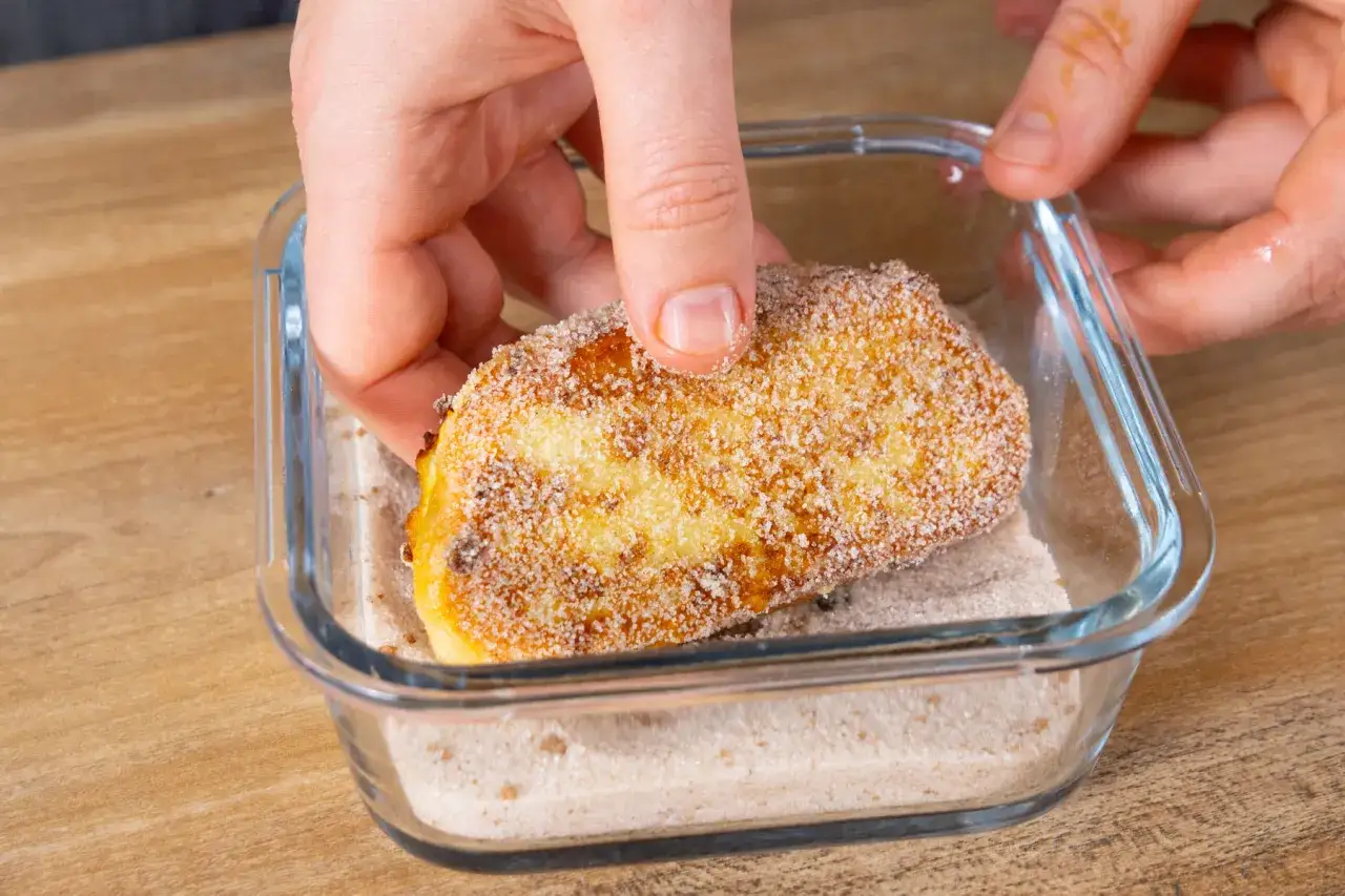 Ein St&uuml;ck Bavesen wird in eine Sch&uuml;ssel mit Zucker und Zimt getaucht. Das ist das bavesen rezept original.