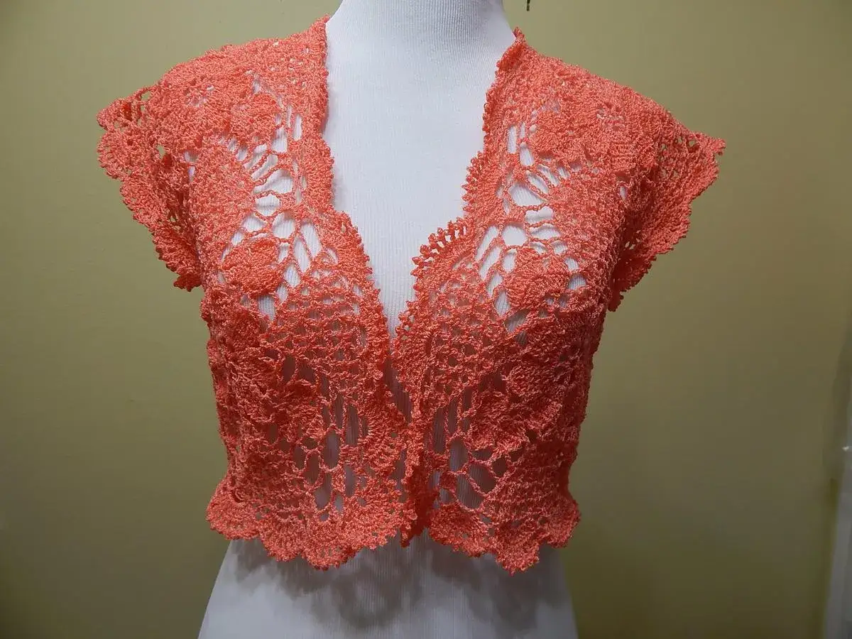 Bolero crochet coral con delicados motivos florales y manga corta, ideal para un toque elegante.