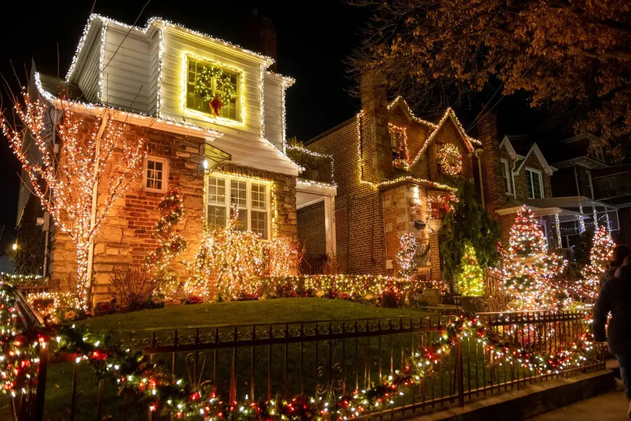 Case di mattoni e pietra illuminate da migliaia di luci natalizie, un esempio perfetto di come addobbare fuori casa per natale con alberi luminosi e ghirlande.