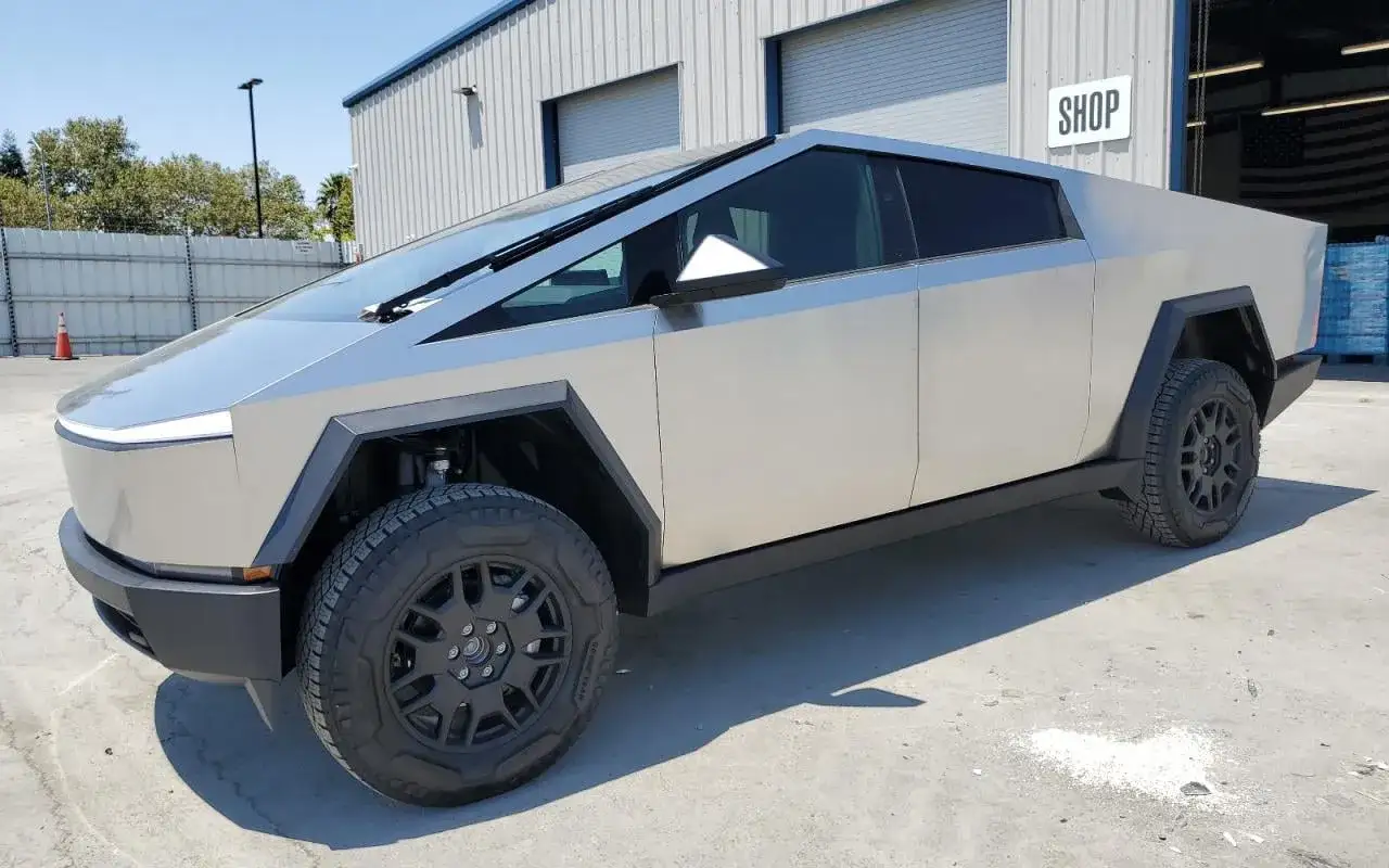 Futurystyczny Tesla Cybertruck, którego cena budzi zainteresowanie, zaparkowany przed budynkiem z napisem