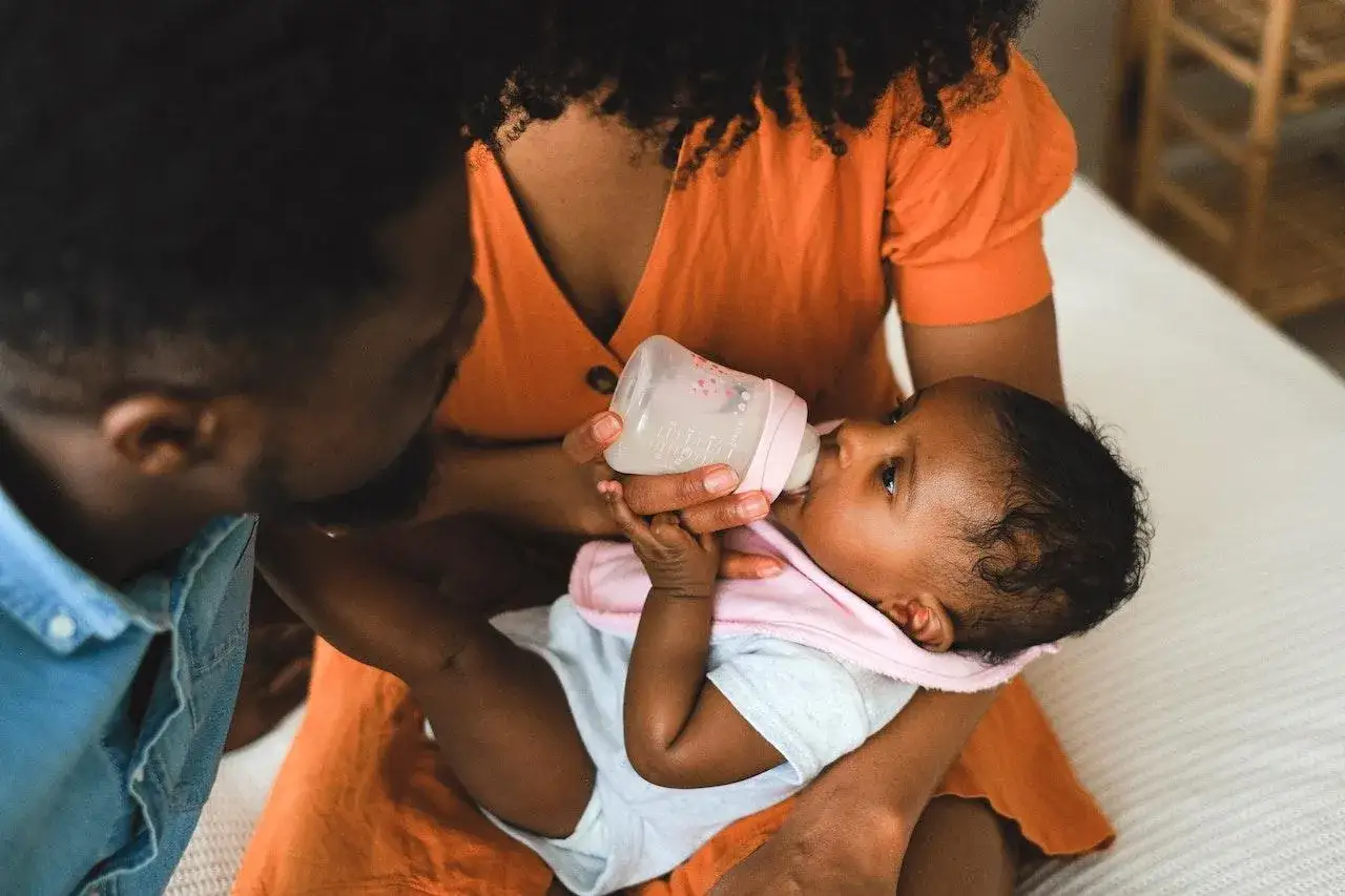 Mamma e pap&agrave; si prendono cura del loro bimbo, praticando l'allattamento misto con amore e attenzione.