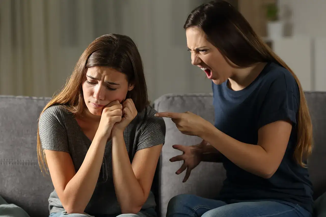 Una sorella urla e punta il dito contro l'altra, che piange. Scene di litigi tra sorelle adulte.