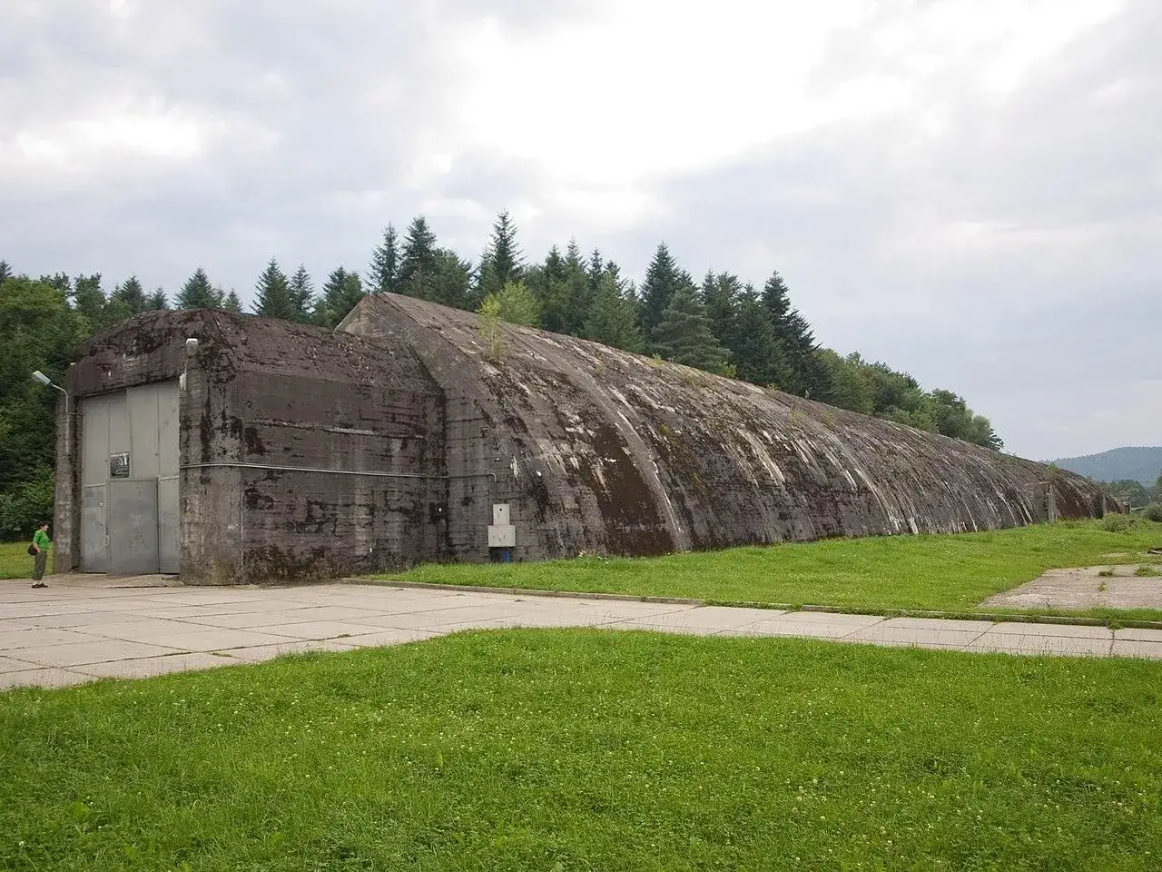 Ogromny, betonowy bunkier w Frysztaku, porośnięty mchem, zamyka drogę do lasu.