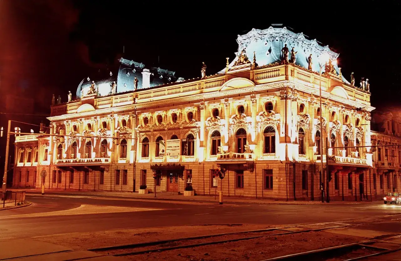 Wspaniały pałac poznański nocą, oświetlony ciepłym blaskiem. Architektura zachwyca detalami i zdobieniami.