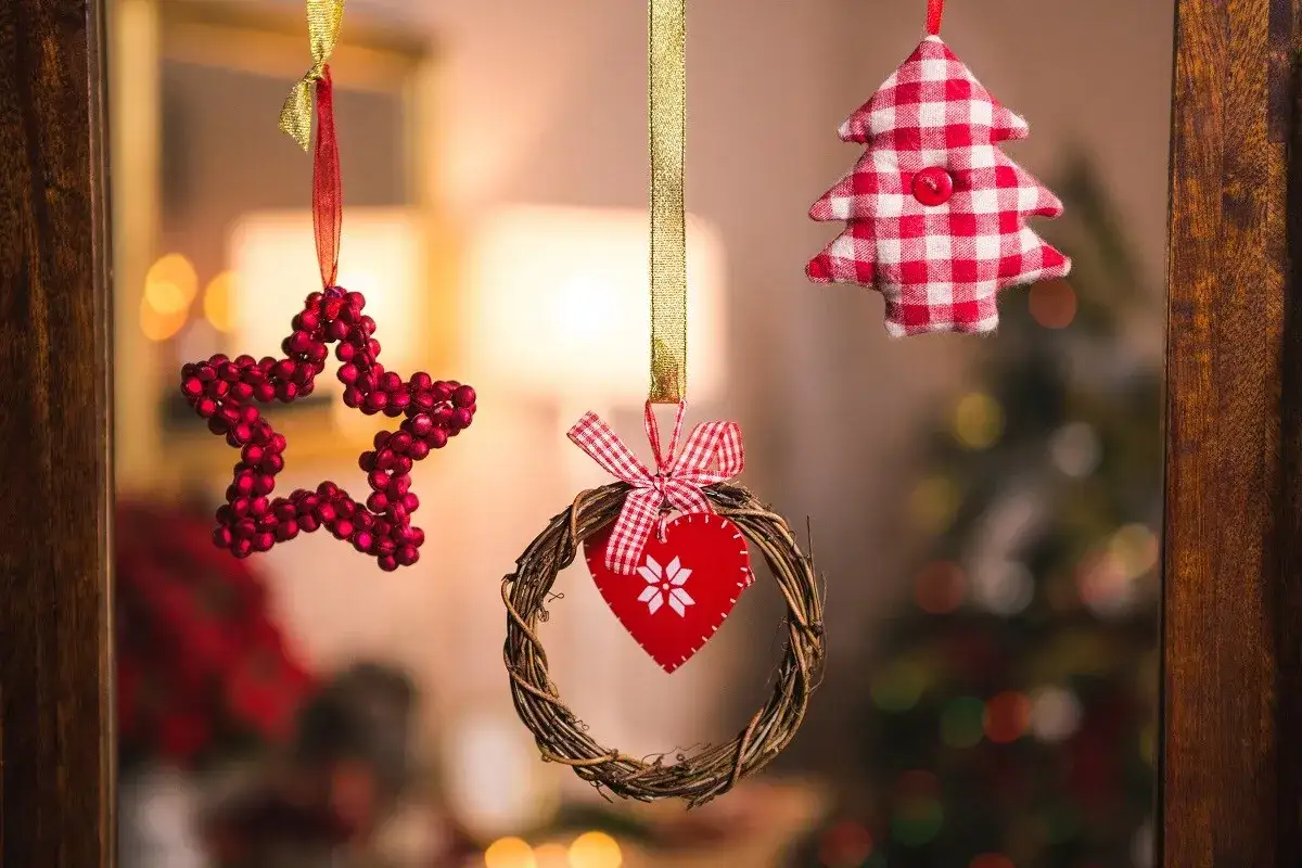 Adornos navide&ntilde;os: estrella roja, coraz&oacute;n en corona de ramas y &aacute;rbol a cuadros. Ideas para decorar una ventana de navidad.