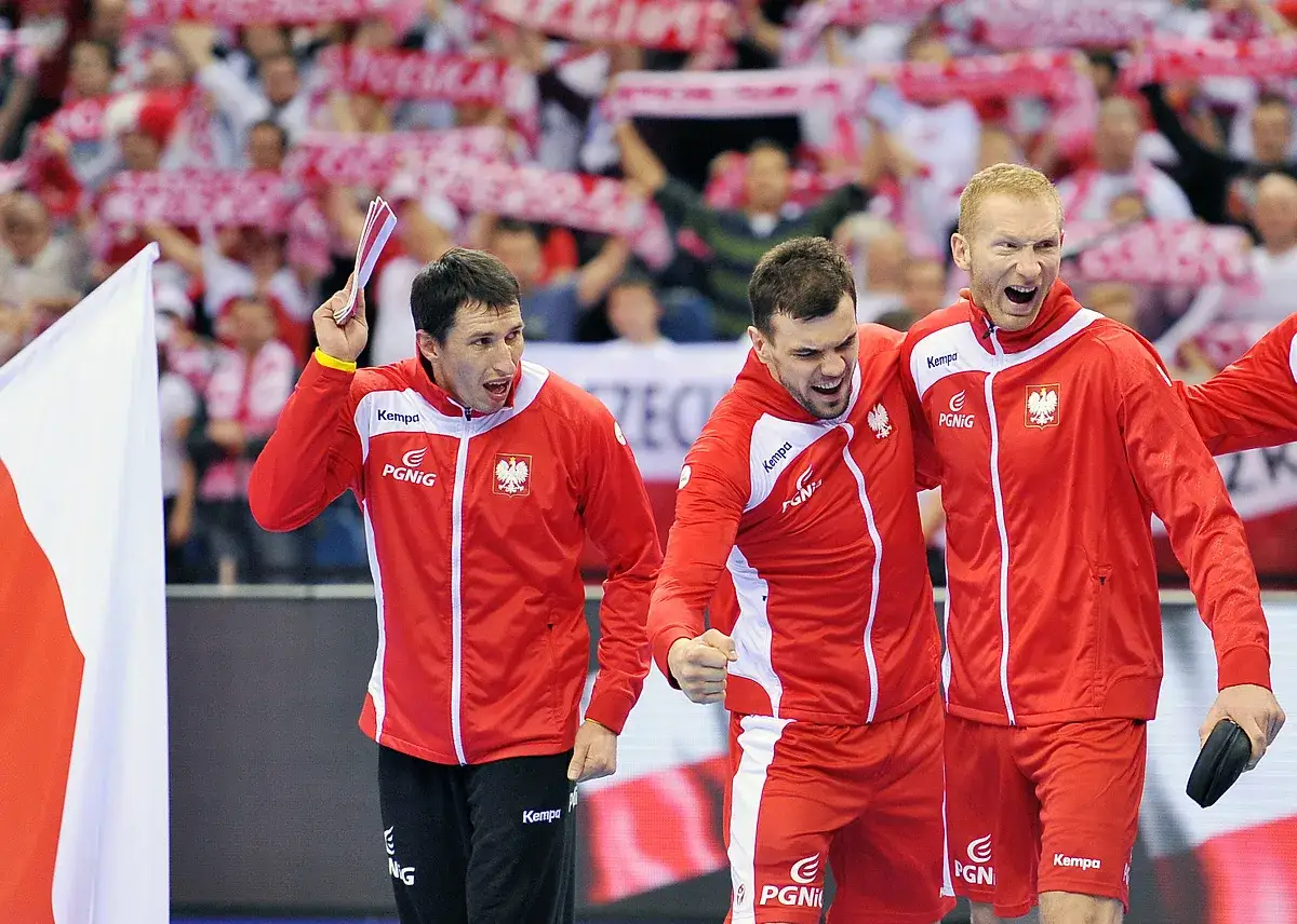 Trzech zawodników w czerwonych strojach z orłem na piersiach, świętujących sukces. To drużyna piłki ręcznej polska!