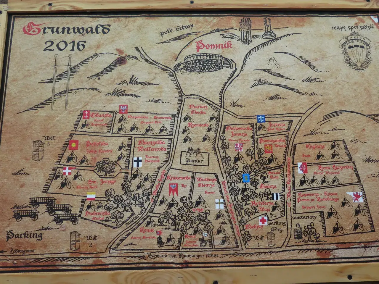 Mapa historyczna z 2016 roku, pokazująca rozstawienie wojsk i obozów, gdzie leży Grunwald. Widoczne namioty, flagi, wozy i nazwy oddziałów.