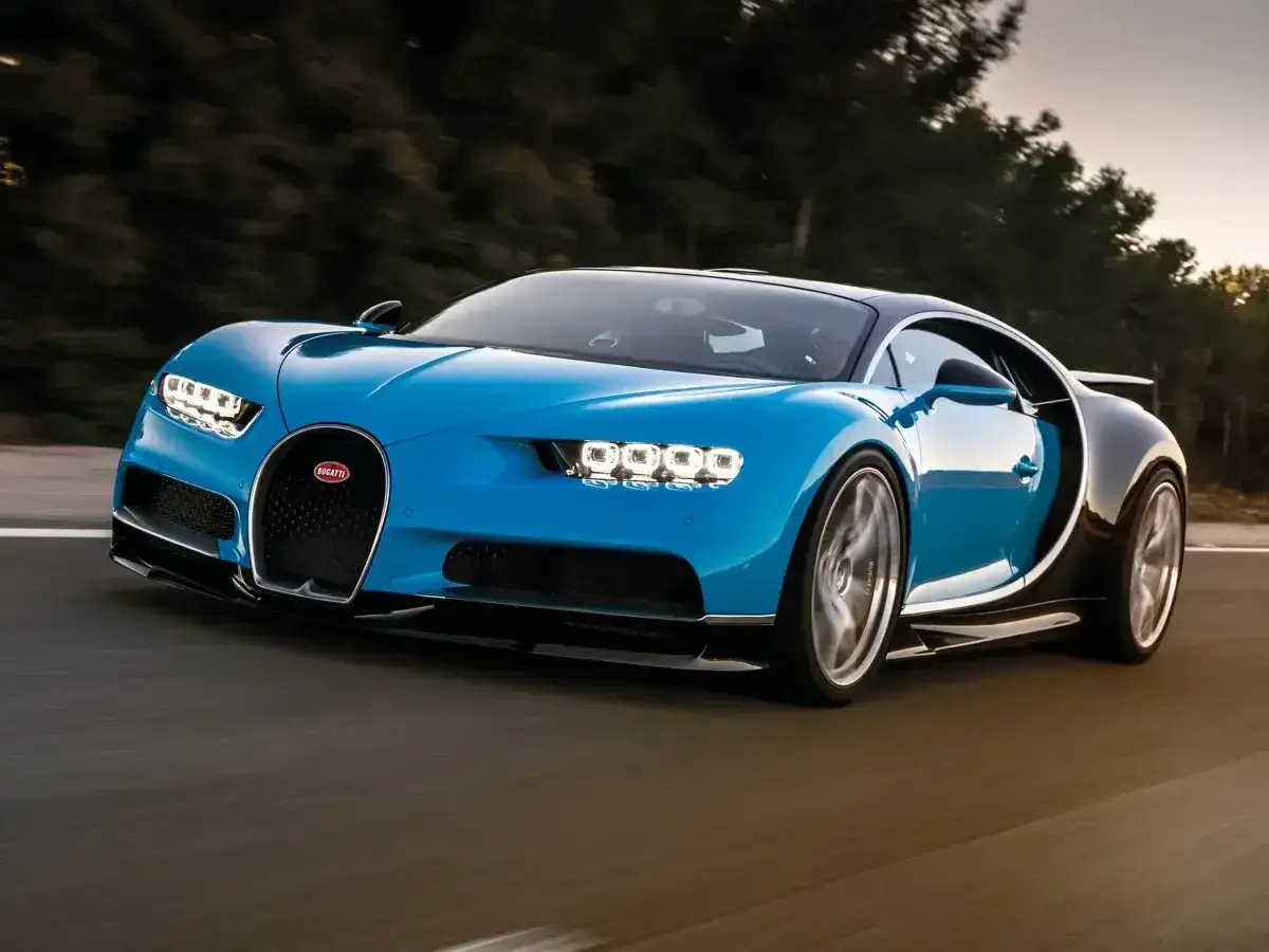 Niebieski Bugatti Chiron pędzi po drodze. Jego cena jest astronomiczna, ale wrażenia z jazdy bezcenne.