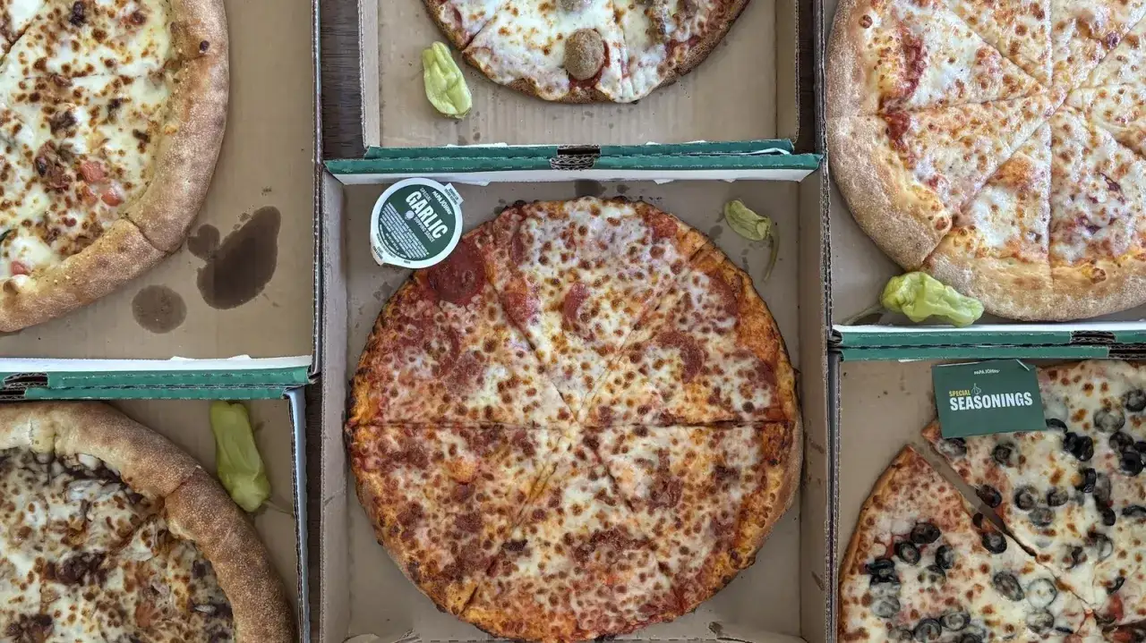 Kilka pizz w pudełkach, sos czosnkowy i papryczki. Czy pizza to fast food? Szybka odpowiedź: tak!