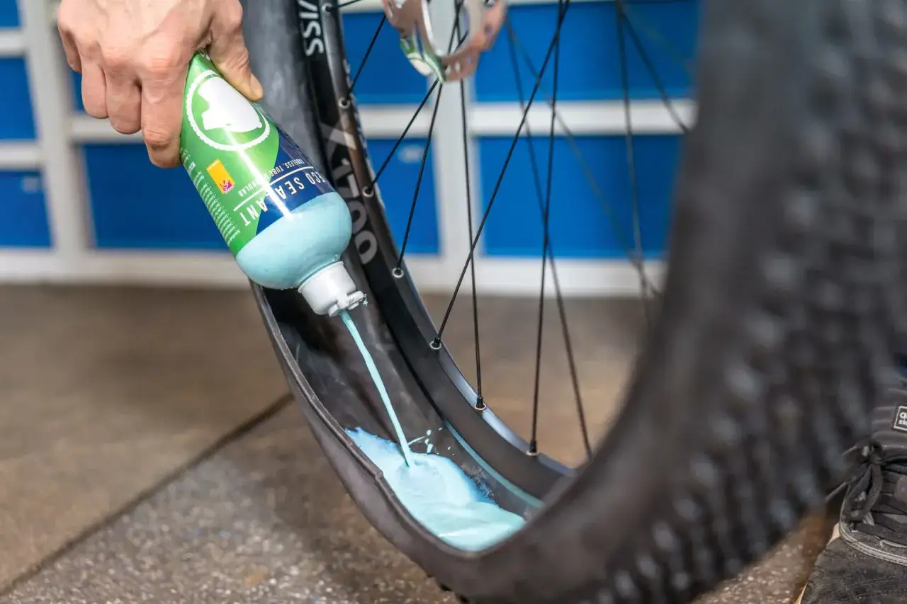 Flüssigkeit wird in einen MTB-Reifen gegossen, um ihn für den Wechsel vorzubereiten.