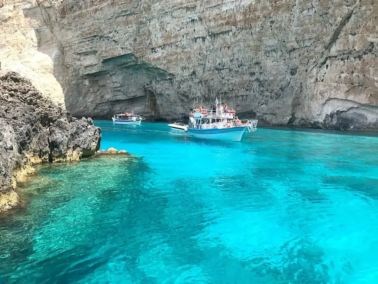Turkusowa woda i łodzie pełne turystów przy skalnych klifach. Idealne miejsce na zakynthos wycieczki fakultatywne.