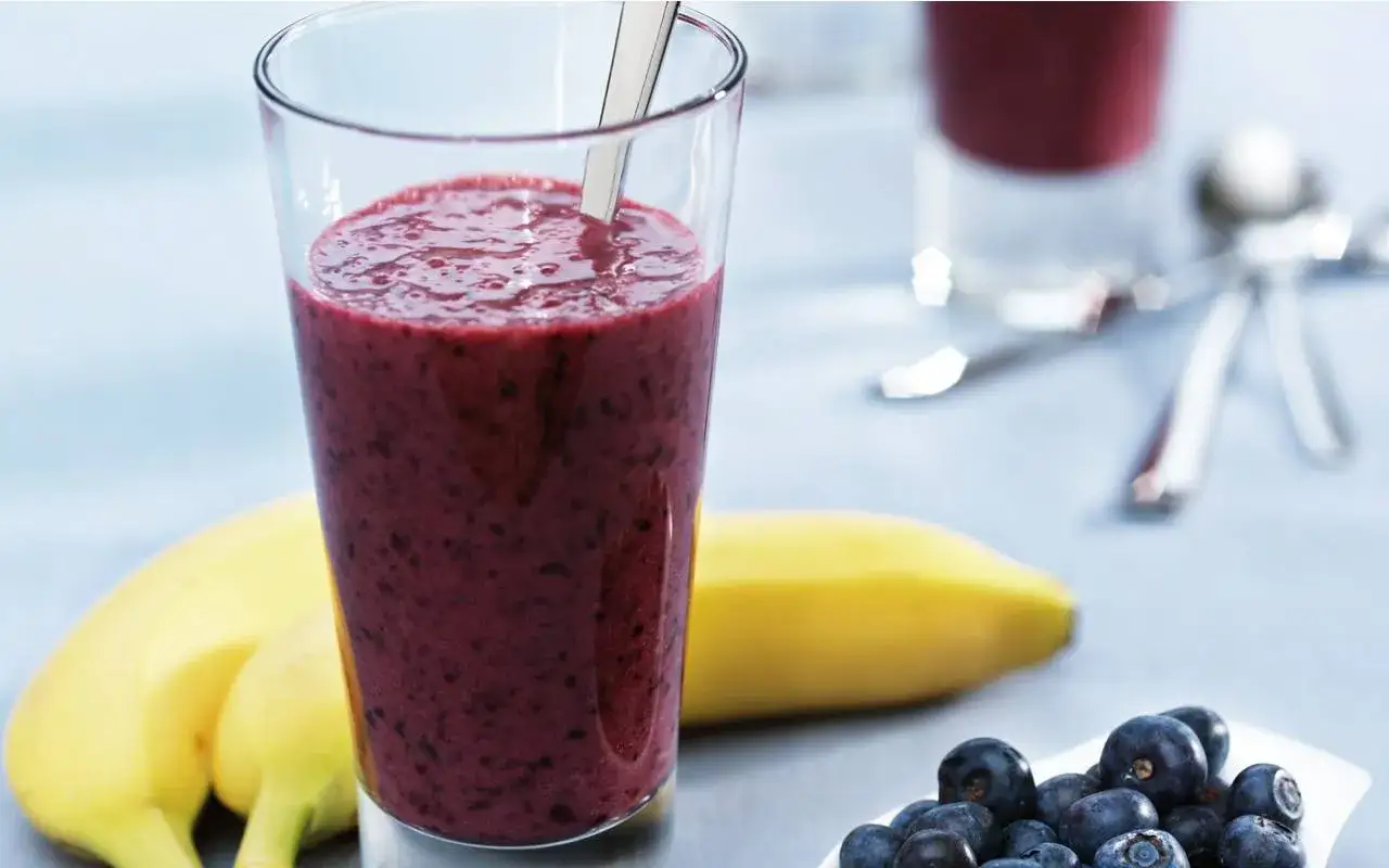 En glas med proteinrik smoothie, bananer och bl&aring;b&auml;r. Perfekt f&ouml;r en energifylld start p&aring; dagen.