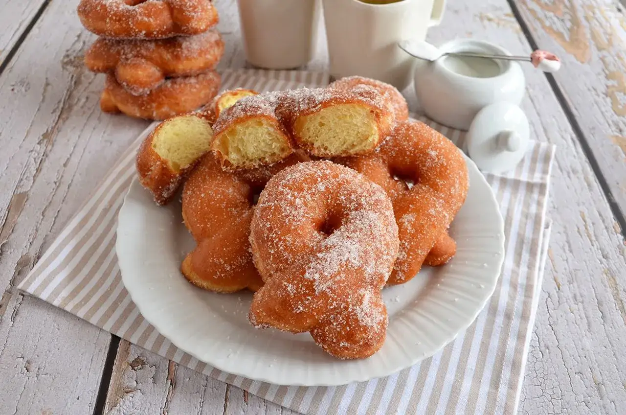 Graffe senza patate, soffici e dorate, ricoperte di zucchero. Perfette per la colazione o una pausa golosa.