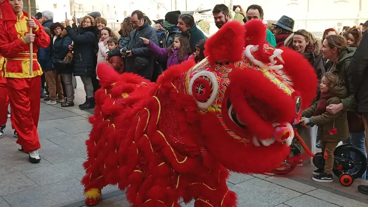 Danza del león rojo en Zaragoza, parte de la agenda cultural. Niños observan fascinados.