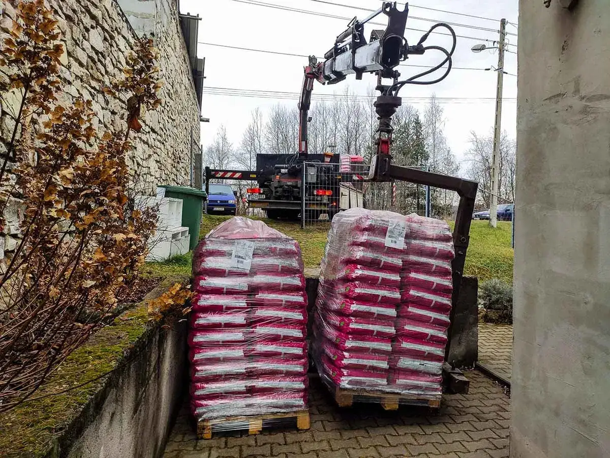 Dwie palety z workami, przygotowane do załadunku przez dźwig. Może to być dostawa z KWK Bobrek, warto sprawdzić cennik.