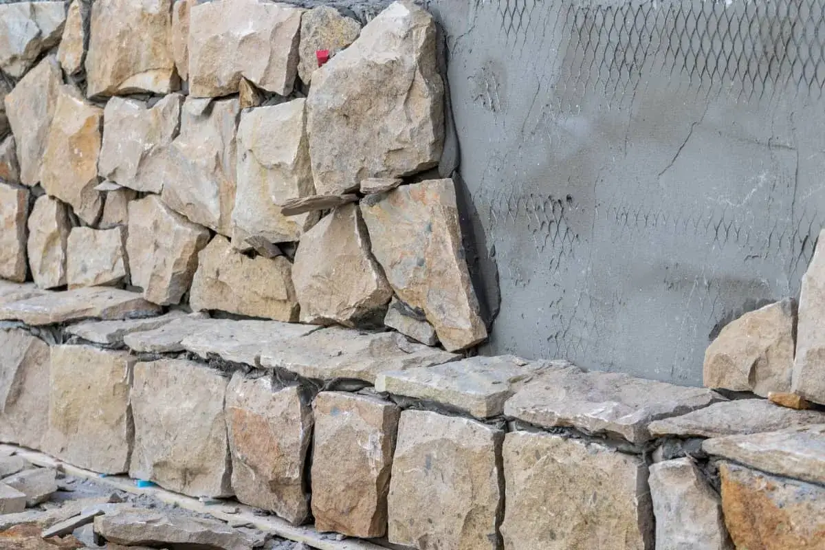 Construcción de muros de piedra natural, mostrando diferentes tipos de paredes y su colocación.