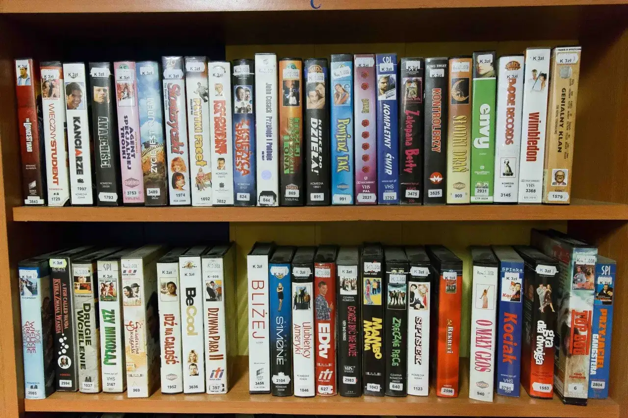 Półka pełna kaset VHS z filmami, m.in.