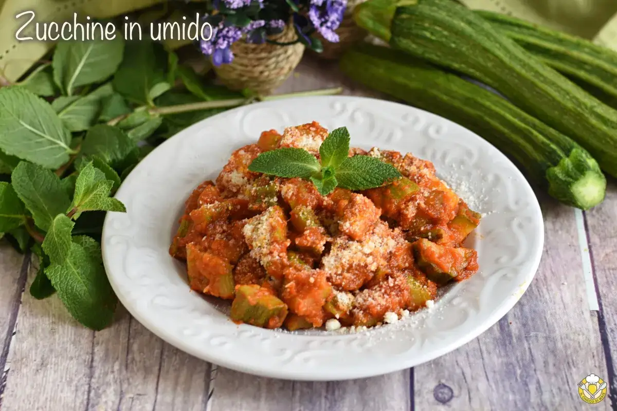 Zucchine in umido, un piatto saporito con zucchine a cubetti in salsa di pomodoro, guarnito con parmigiano e menta fresca.