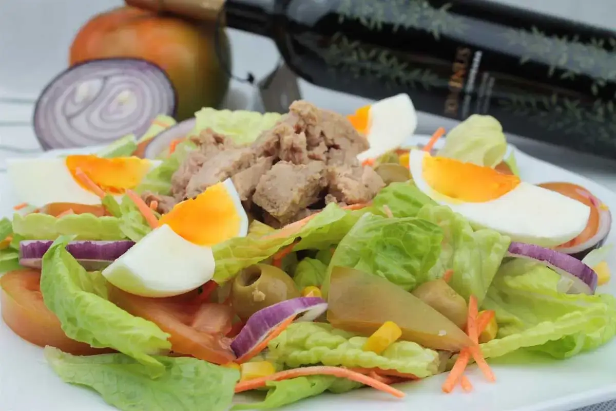 Ensalada mixta fresca con at&uacute;n, huevo duro, tomate, cebolla morada y aceitunas.