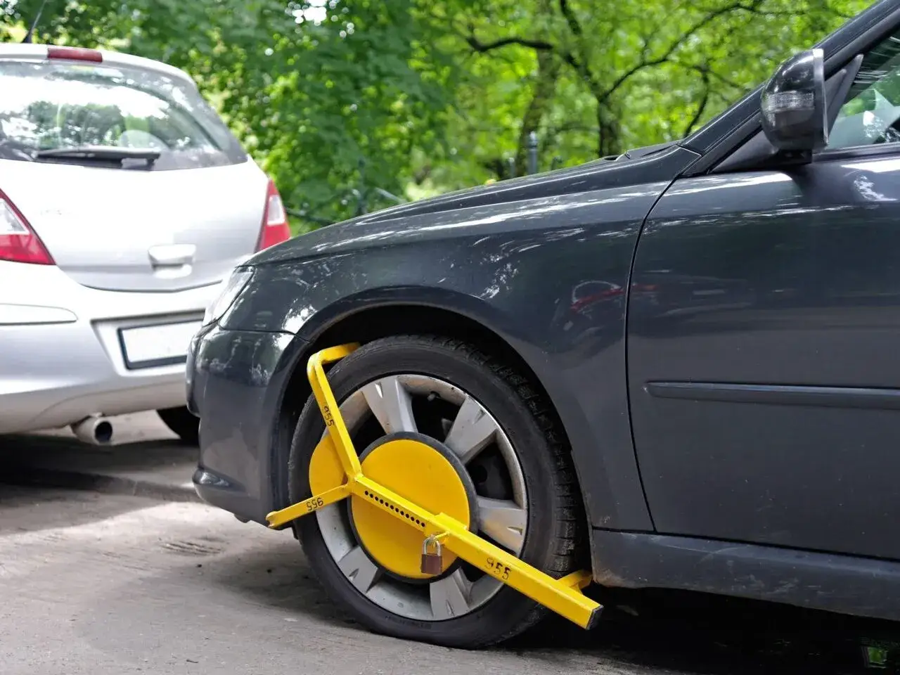 Bloccaggio ruota giallo su un'auto scura, un monito su come proteggere l'auto dal pignoramento.