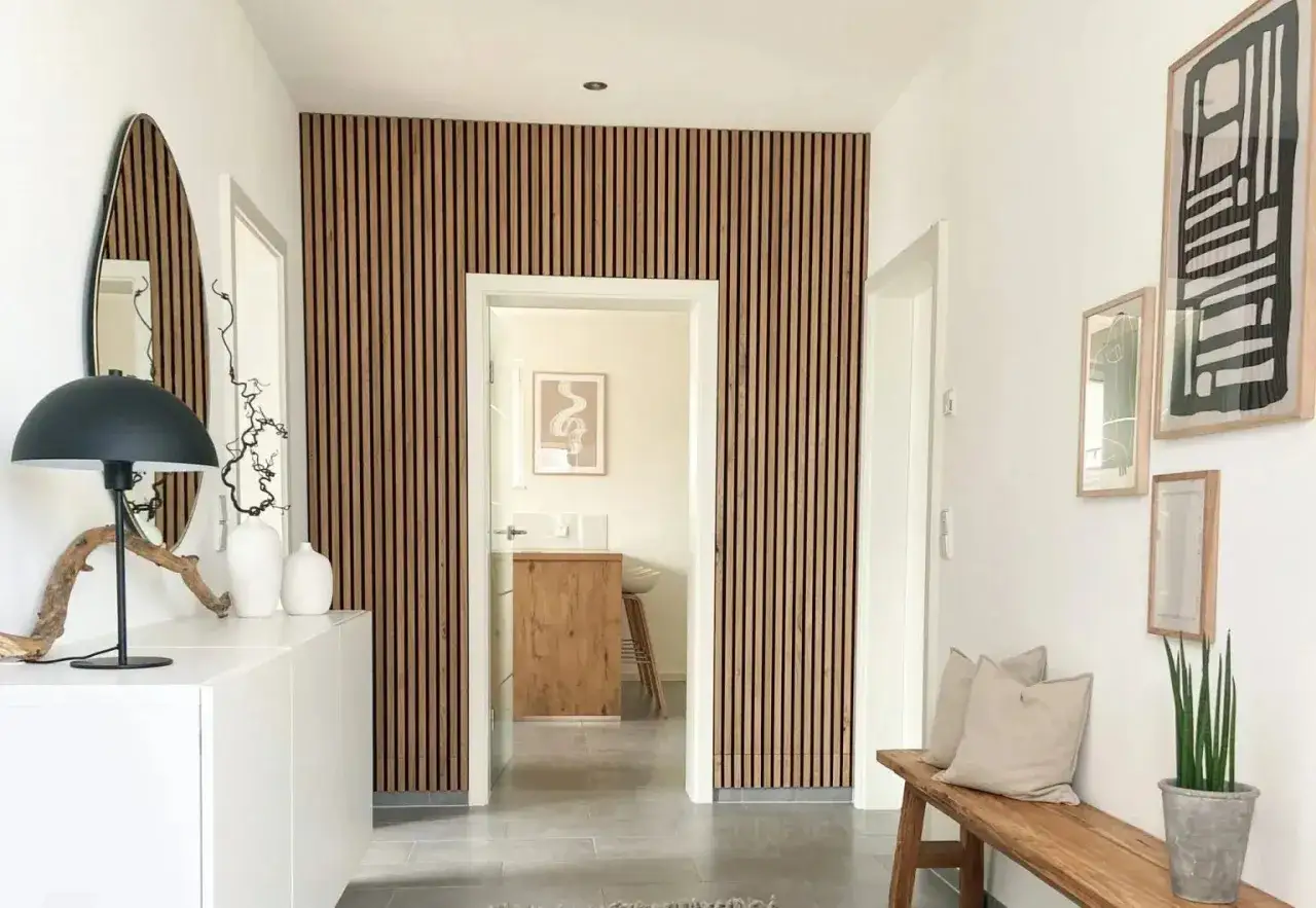 Moderner Flur mit Akustikpaneelen an der Wand, die eine DIY-Garderobe erg&auml;nzen. Ein Spiegel, eine Lampe und eine Bank schaffen Gem&uuml;tlichkeit.