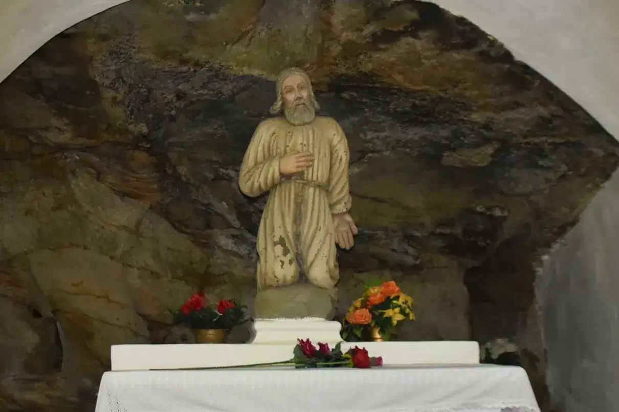 Kamienna grota, w której 13 lipca modli się postać świętego. Obok kwiaty.