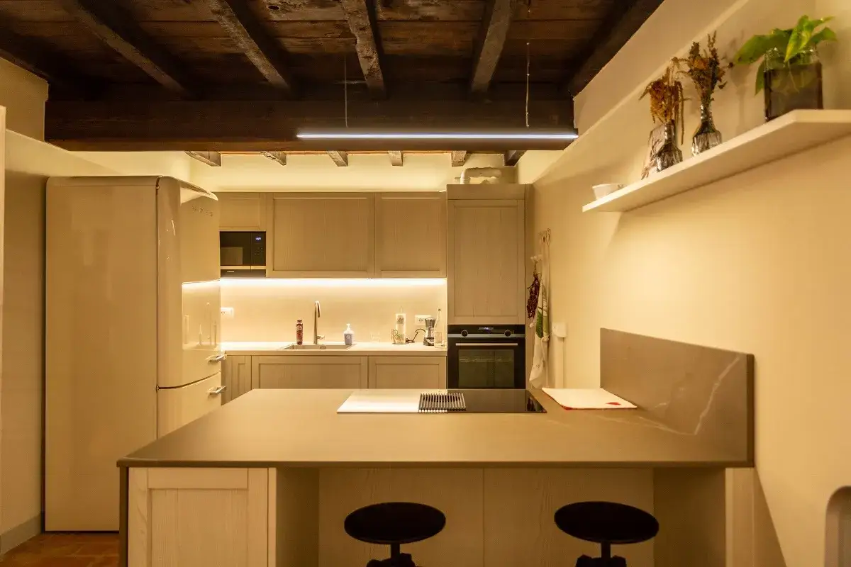 Cucina moderna con isola centrale, elettrodomestici in acciaio e un'illuminazione soffusa che crea un'atmosfera accogliente, un vero lux lumen.