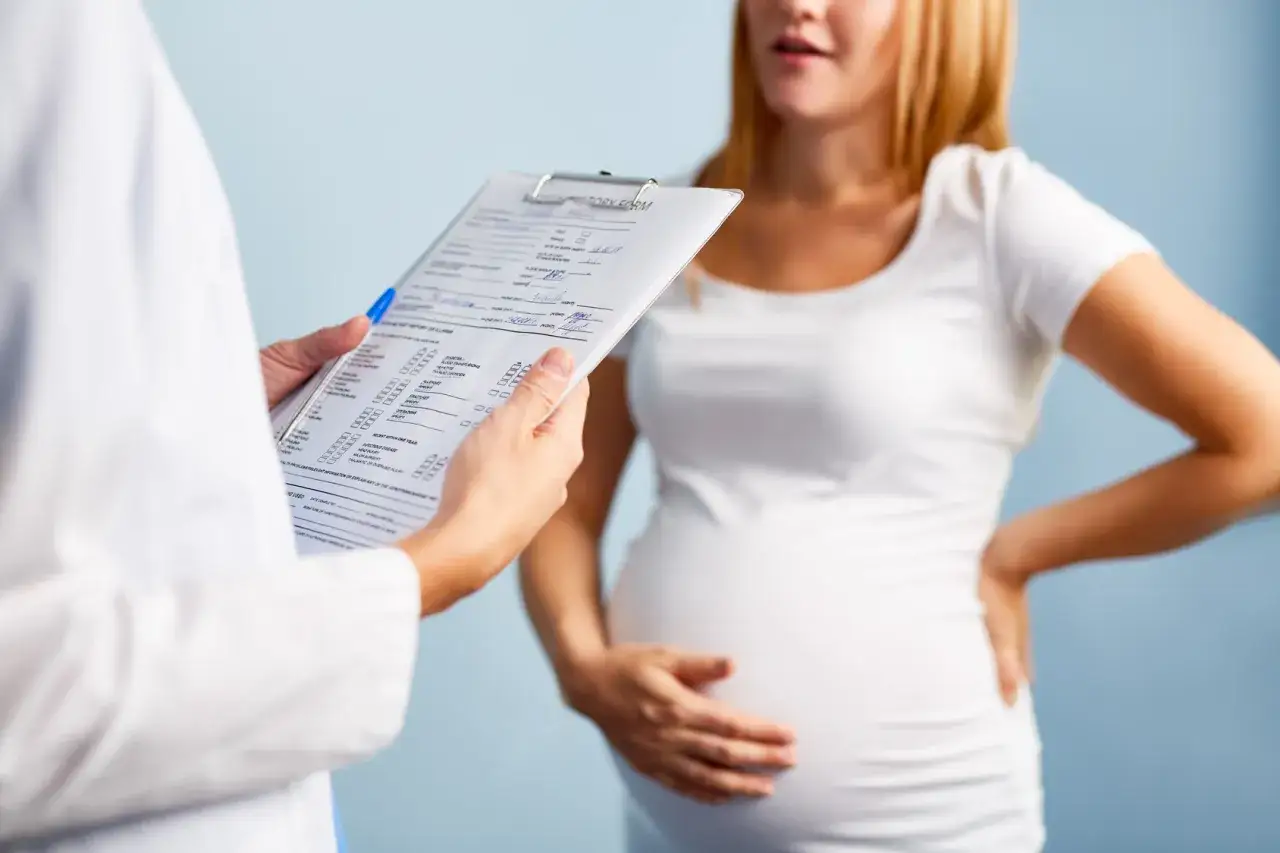 Lekarz omawia z ciężarną pacjentką objawy, w tym potencjalne zatrzymanie moczu w ciąży, wypełniając formularz medyczny.