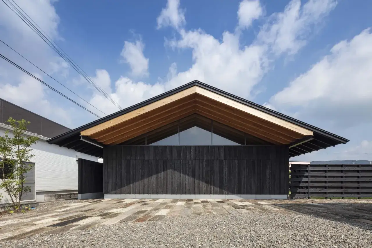 Maison moderne avec fa&ccedil;ade en bois brul&eacute; japonais, toiture en bois apparent et grand ciel bleu.