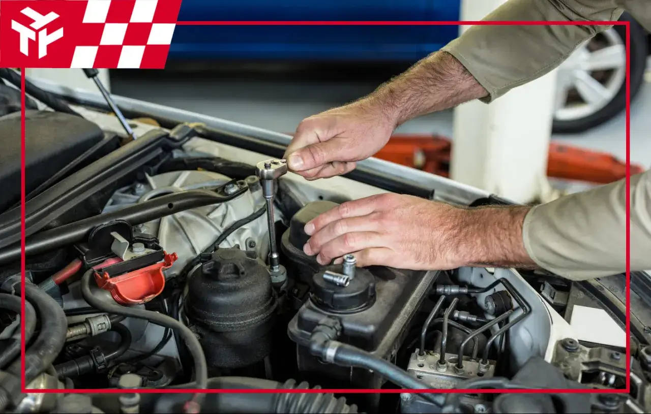 Mechanik dokonuje czynności związanych z płukaniem silnika ropą, używając klucza nasadowego do precyzyjnych prac.