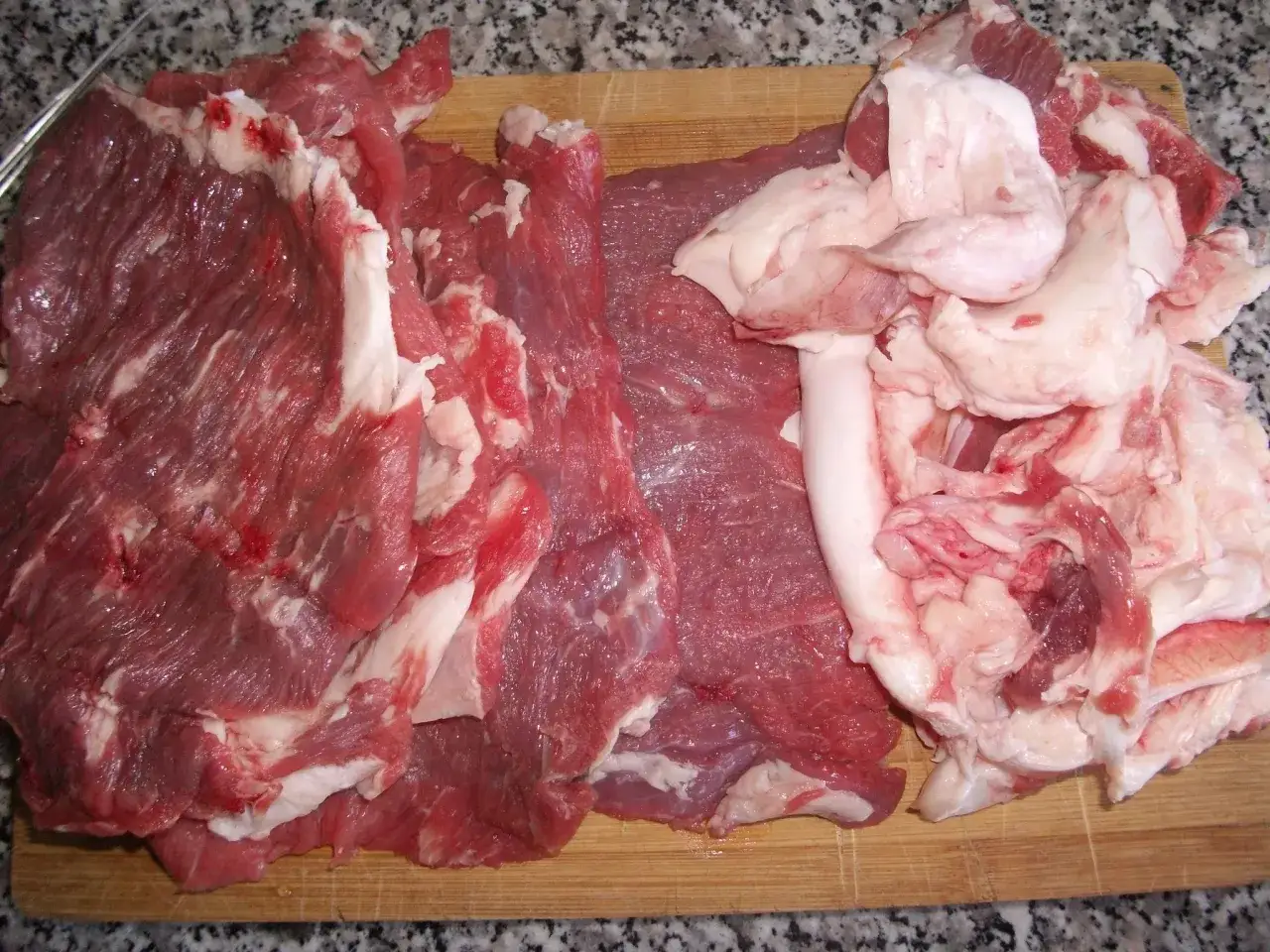 Carne cruda, grasso e un coltello su un tagliere, pronti per preparare un saporito rag&ugrave; napoletano.