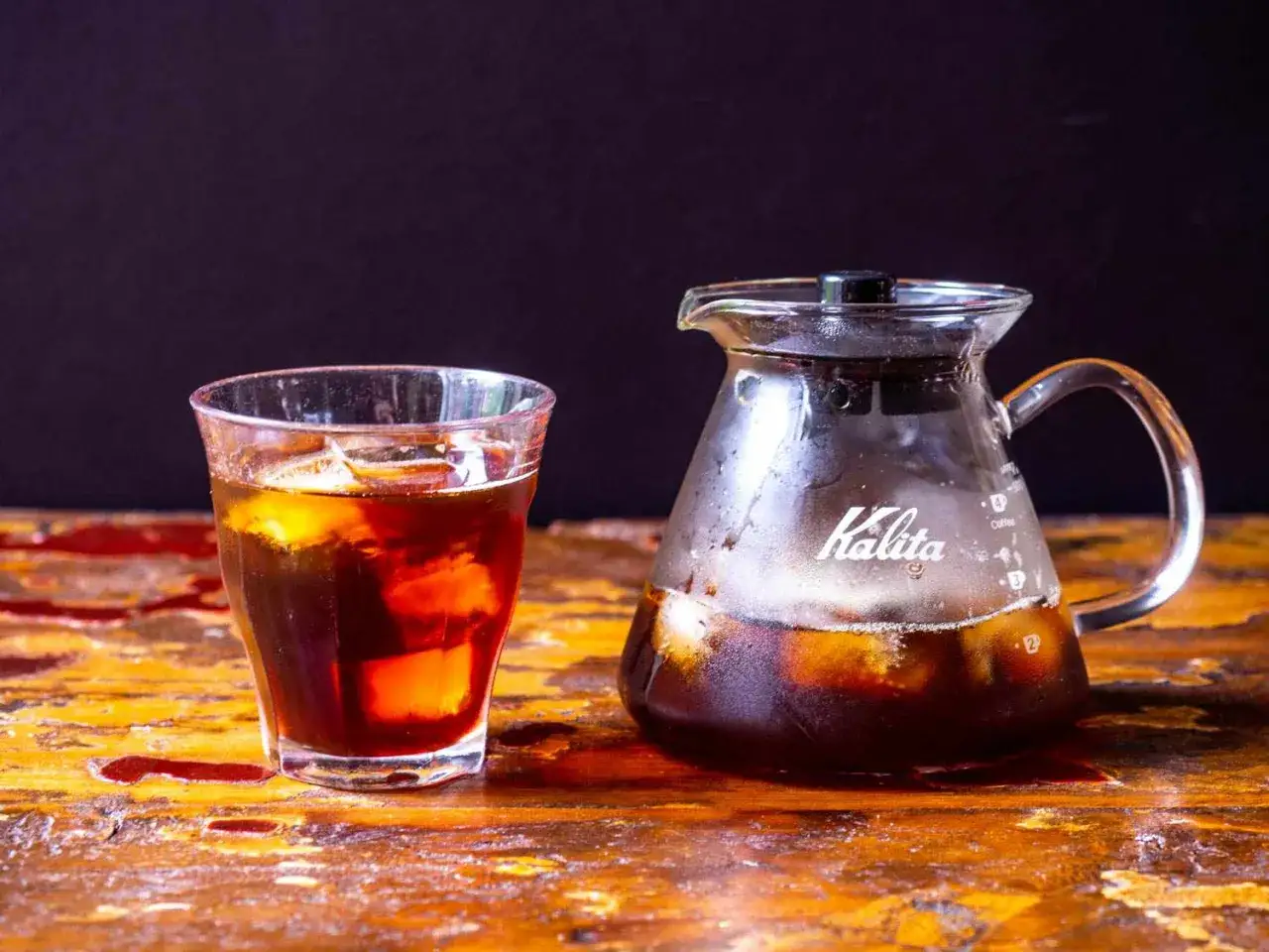 Szklanka z lodem i dzbanek Kalita z ciemnym napojem. Idealne na upalne dni, zastanawiasz się, jaka kawa do cold brew?