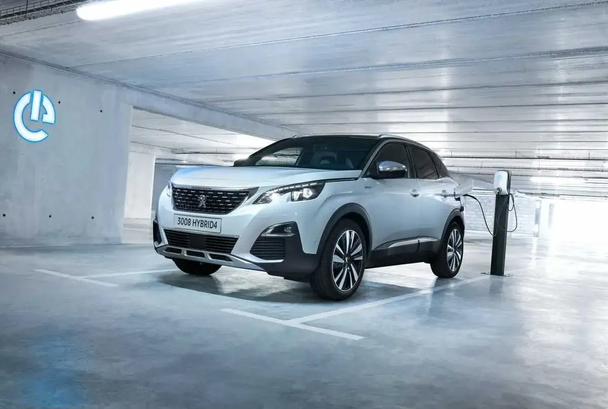 Un Peugeot 3008 Hybrid4 plateado se carga en un aparcamiento moderno.