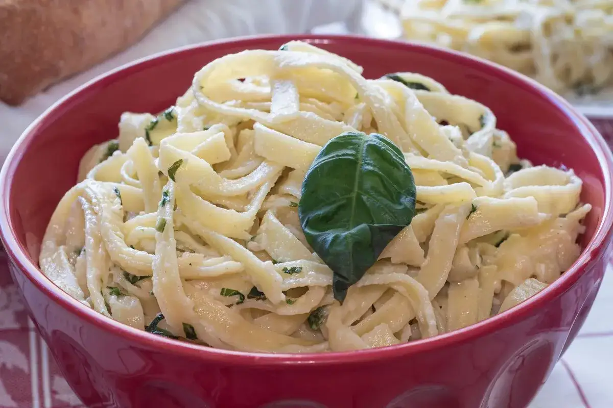 Tagliatelle condite con un delizioso sugo burro e salvia, guarnite con una foglia di basilico fresco.