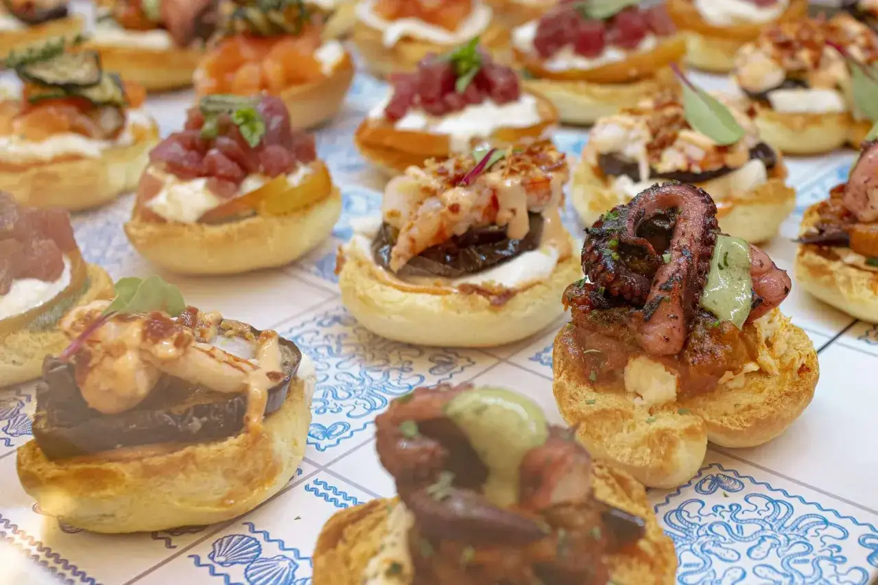 Varietà di antipasti di pesce su pane croccante: polpo grigliato, gamberi, tonno e salmone. Un tripudio di sapori marini.